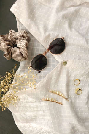 White blouse, retro sunglasses, hair accessories, gold rings and gypsophila flowers. Flat lay.の写真素材