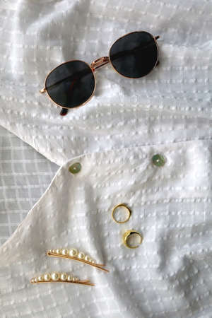 White blouse, retro sunglasses, hair accessories, gold rings and gypsophila flowers. Flat lay.の写真素材