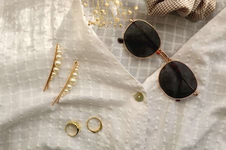 White blouse, retro sunglasses, hair accessories, gold rings and gypsophila flowers. Flat lay.の写真素材