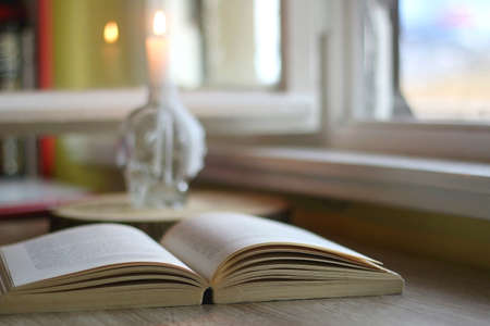 Open book and lit candle on a table. Selective focus.の写真素材