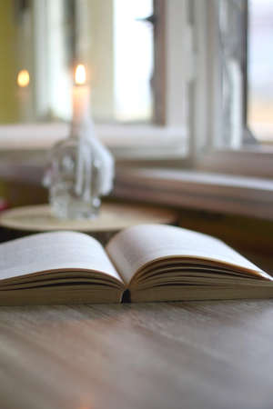 Open book and lit candle on a table. Selective focus.の写真素材