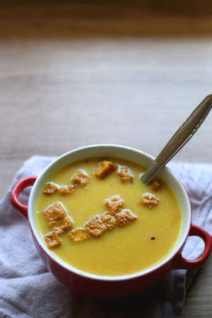 Bowl of vegan pumpkin and tofu curry soup on wooden table. Selective focus.