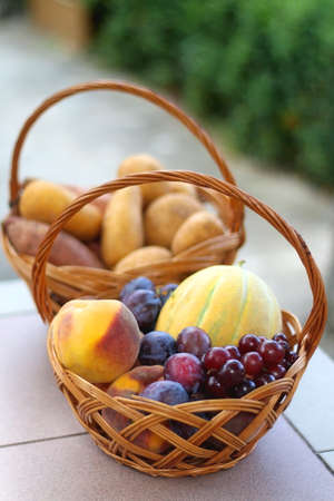 Two baskets full of fresh fruit and vegetable in a garden. Selective focus.の写真素材