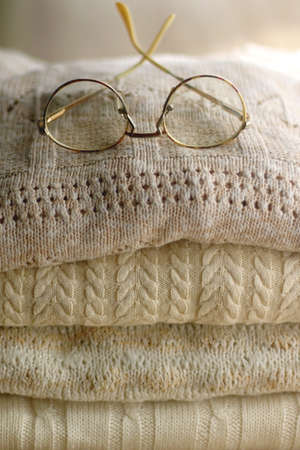 Pile of beige sweaters and retro eyeglasses. Selective focus.の写真素材