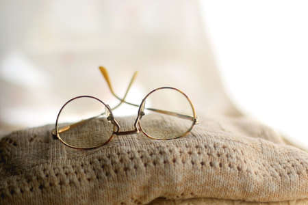 Pile of beige sweaters and retro eyeglasses. Selective focus.の写真素材
