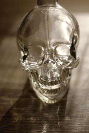 Glass skull on wooden table. Halloween decoration. Selective focus.の写真素材