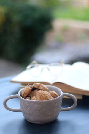 Bowl of cinnamon cookies, hardcover books and reaing glasses. Selective focus.の写真素材