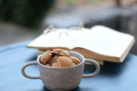 Bowl of cinnamon cookies, hardcover books and reaing glasses. Selective focus.