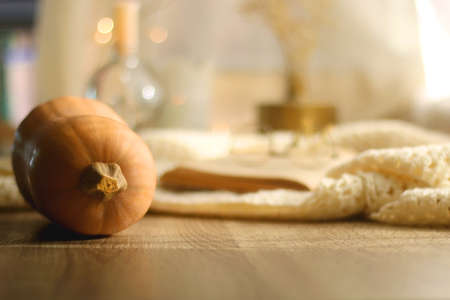 Butternut squash, soft blanket, open book, reading glasses and lit candles. Autumn season, hygge at home. Selective focus.の写真素材