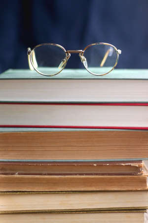 Stack of hardcover books and reading glasses. Selective focus.の写真素材