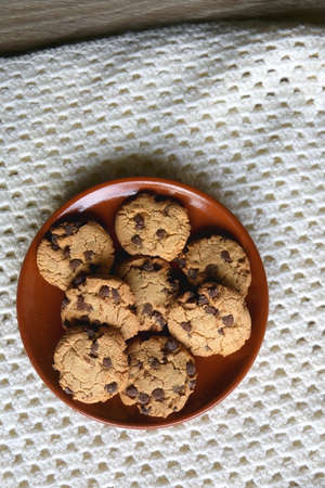 Plate of chocolate chip cookies and knitted blanket. Hygge at home. Flat lay.