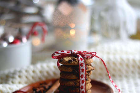 Stack of chocolate chip cookies tied with ribbon, cinnamon, anise, various Christmas decorations and...