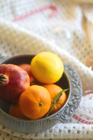 Silver bowl with various fruit, soft blanket and various Christmas decorations. Hygge at home....