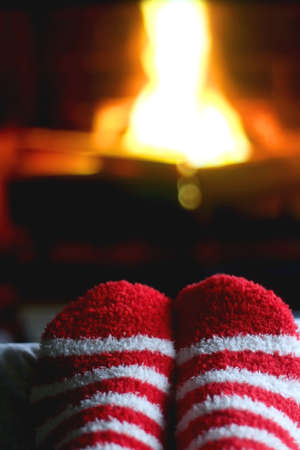 Feet in striped Christmas socks in front of a fireplace. Selective focus.