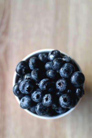 Cup of fresh blueberries on wooden table. Flat lay.の写真素材