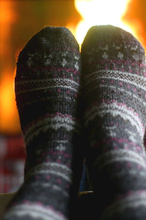 Feet in warm gray socks in front of a fireplace. Selective focus.