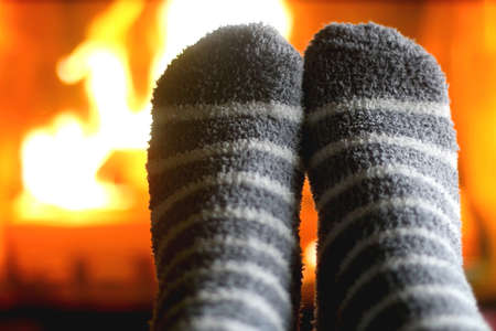Feet in warm gray socks in front of a fireplace. Selective focus.の写真素材