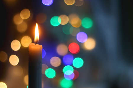 Lit candle and beautiful colorful bokeh lights. Selective focus.の写真素材