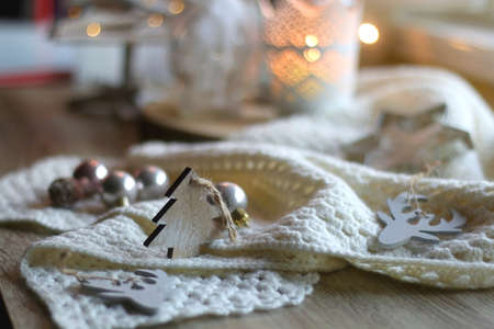 Various Christmas decorations in neutral colors, soft knitted blanket and lit candles. Selective focus.の写真素材