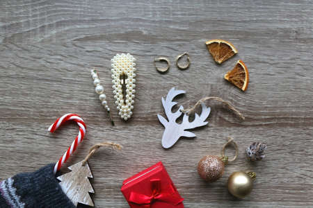 Wool stocking with small presents and Christmas decorations on wooden background. Flat lay.