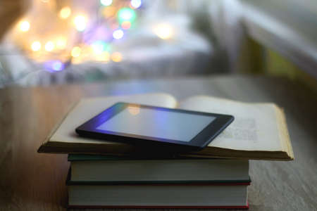 Stack of books, e-reader and colorful bokeh lights in the background. Selective focus.の写真素材