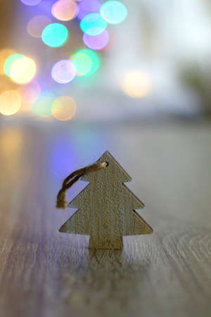 Wooden Christmas tree ornament on the table and colorful bokeh lights. Selective focus.の写真素材