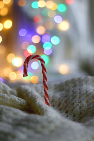 Candy cane and soft blanket. Colorful bokeh lights in the background. Selective focus.の写真素材