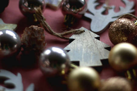 Wooden Christmas ornaments, gold and metallic baubles and pine cones on pink background. Selective...