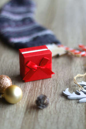 Wool stocking with small presents and Christmas decorations on wooden background. Selective focus.の写真素材