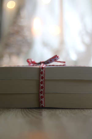 Stack of paperback books, wrapped with ribbon and decorated for Christmas. Giving books for present....