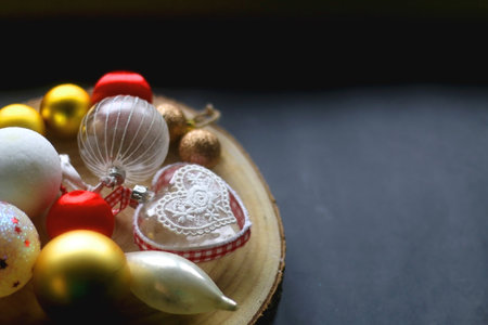 Wooden tray with Christmas ornaments in red, gold and white tones. Dark background, selective focus.