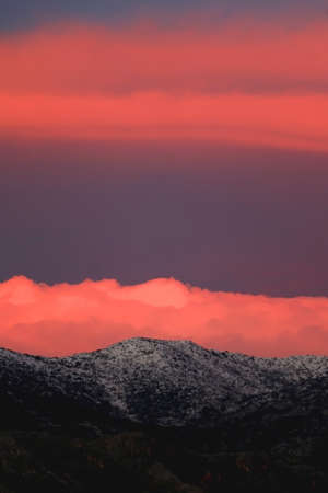 Mountain peaks covered in snow and pink clouds in the sky. Beautiful winter sunset in Croatia.の写真素材