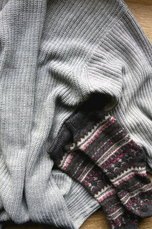 Gray sweater, warm gloves and socks on wooden background. Top view.の写真素材
