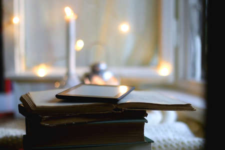 Stack of books, digital e-reader and lit candles. Selective focus.の写真素材