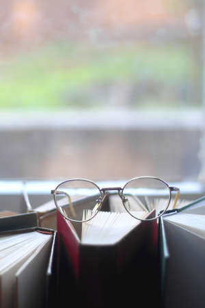 Pile of hardcover books and reading glasses. Selective focus.の写真素材