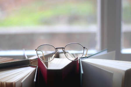 Pile of hardcover books and reading glasses. Selective focus.