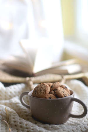Bowl of chocolate chip cookies, soft knitted basket, wicker basket and candle holder with lit...