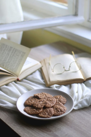 Plate of healthy gluten free cookies, open books and reading glasses on the table. Selective focus.の写真素材