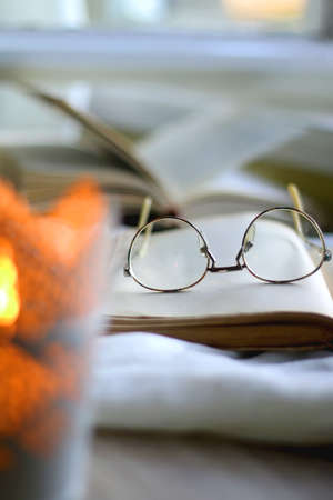 Open books, reading glasses and lit candle on the table. Selective focus.の写真素材
