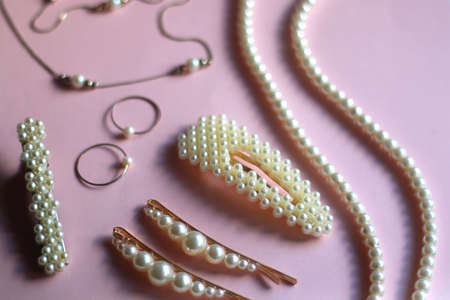 Various pearl jewelry and hair accessories on pink background. Selective focus.の写真素材