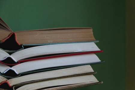 Stack of open vintage hardcover books on the shelf. Selective focus, green background.