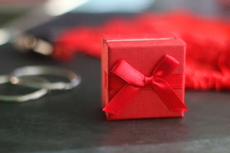 Small red giftbox, red lipstick, silver earrings and lace underpants. Valentine's Day objects on dark background. Selective focus.の写真素材