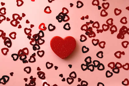 Small red heart and heart shaped confetti on pastel pink background. Flat lay.の写真素材