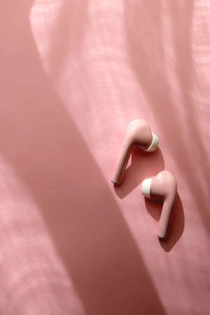 Pink wireless  earphones on pink background. Flat lay.の写真素材