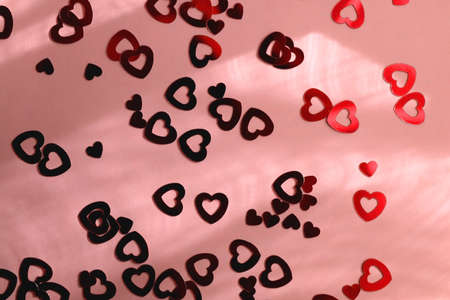 Red heart shaped confetti on pastel pink background. Flat lay.の写真素材