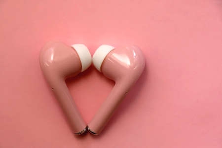 Pink wireless  earphones on pink background. Flat lay.