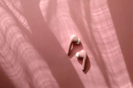 Pink wireless  earphones on pink background. Flat lay.の写真素材