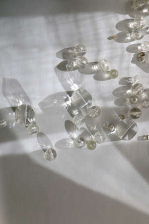 Various transparent beads on white background, illuminated by sunlight and reflectiing light. Flat lay.の写真素材