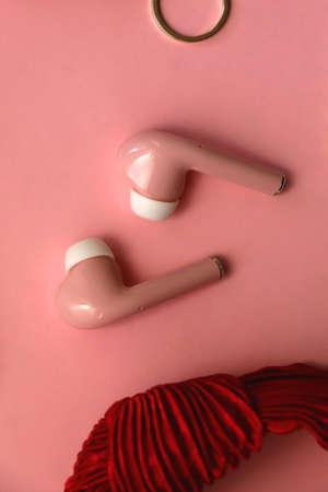 Pink  earphones, red hairband, pearl hair clips, gold earrings and ring, pink blush and lipstick on pastel pink background. Flat lay.の写真素材