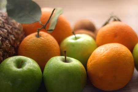 Pineapple, apples, oranges, lemons and kiwis on a wooden table. Selective focus.の写真素材